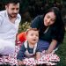 A joyful family enjoying a picnic outdoors during summer. Smiling parents with their baby on a blanket.
