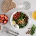 Top view of a nutritious breakfast with salad, eggs, bread, and juice, perfect for a healthy start.