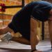 Man working out indoors, performing push-up exercise against a brick wall.